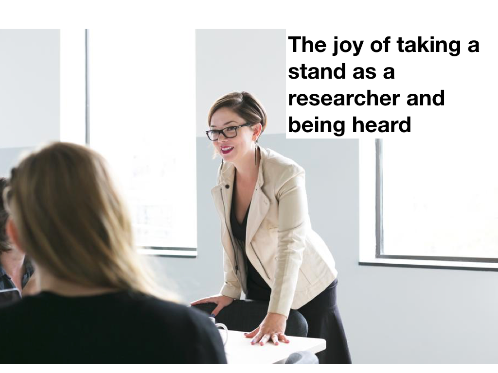 UX researcher standing and leading with a smile after sharing a strong, data-supported point of view