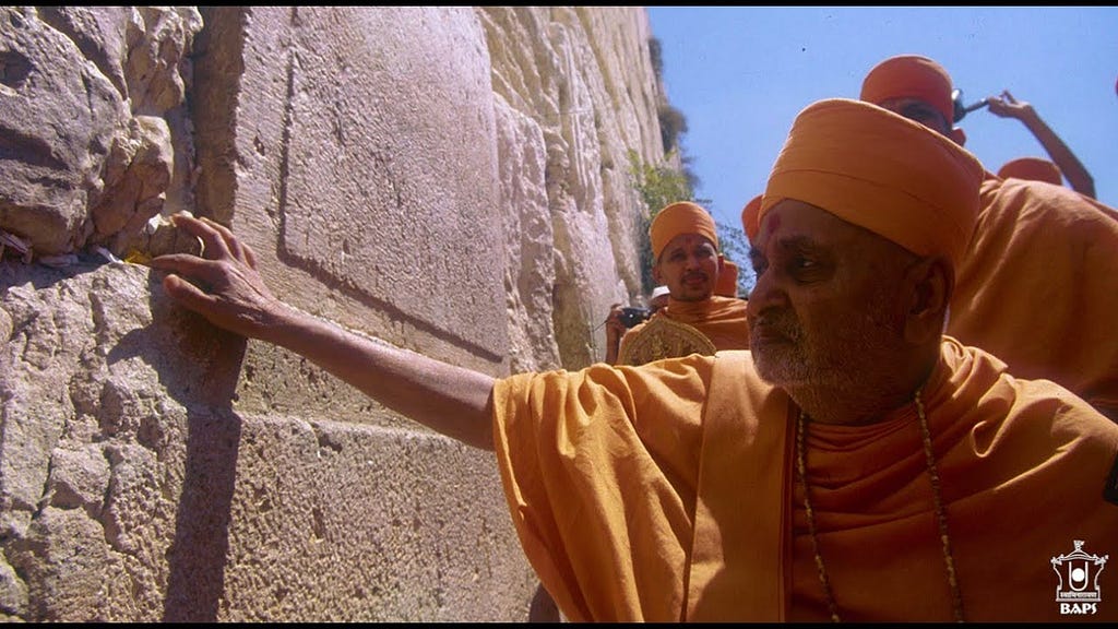 Pramukh Swami Maharaj placing a flower in the crack on the Western Wall