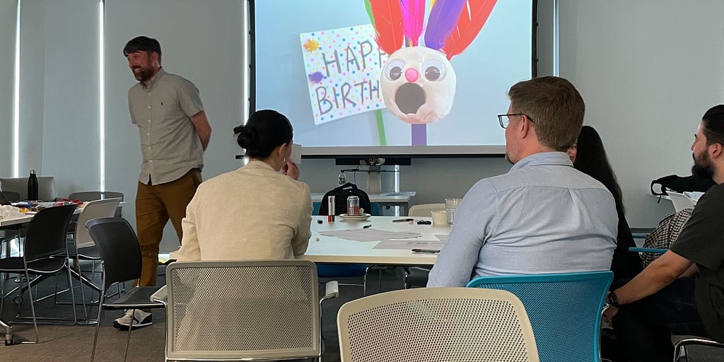 Man presenting in front of a screen. The screen has a character with a shocked face and ‘Happy Birthday’ sign, to show the surprised emotion.