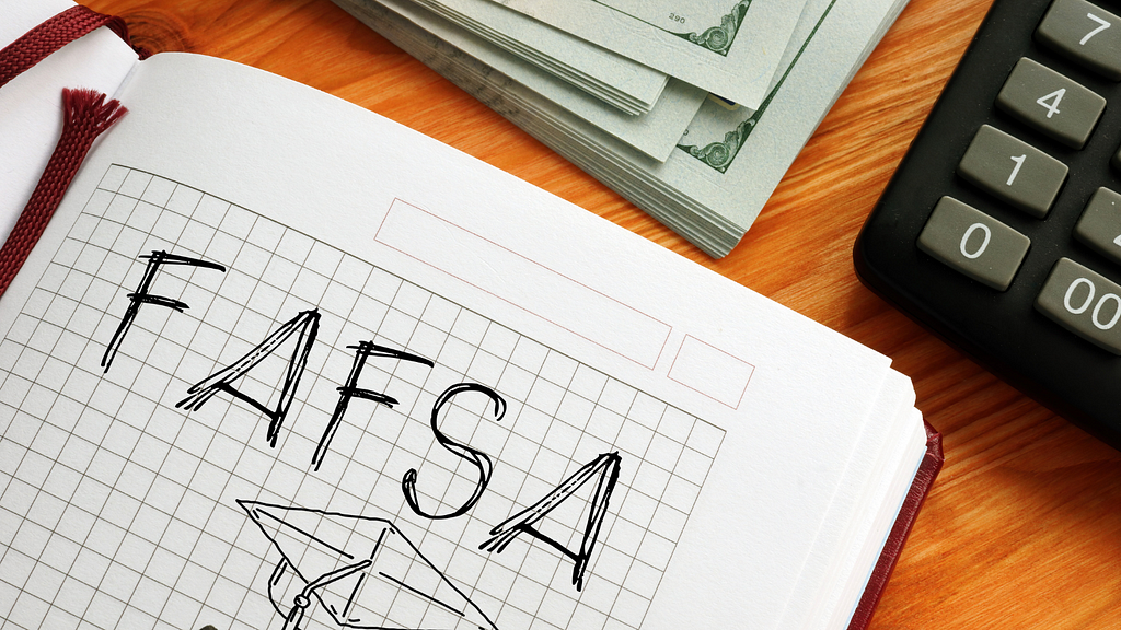FAFSA drawn on notebook paper with sketch of graduation hat. Stack of money and calculator shown.
