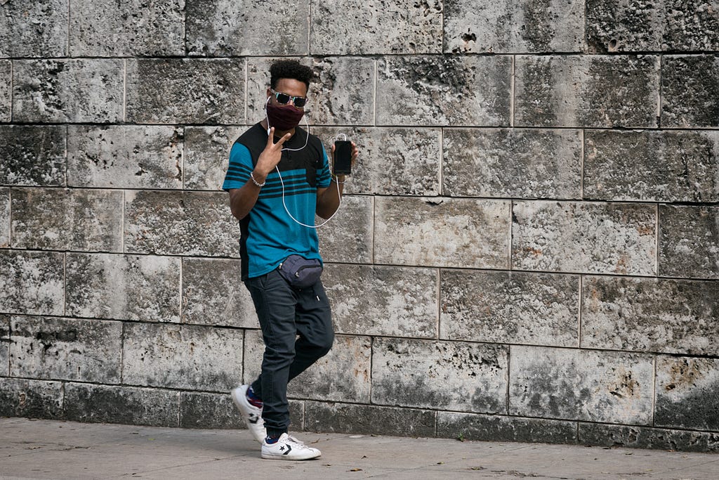 a young man with a cell phone walks connected to the Internet on a street in Cuba.