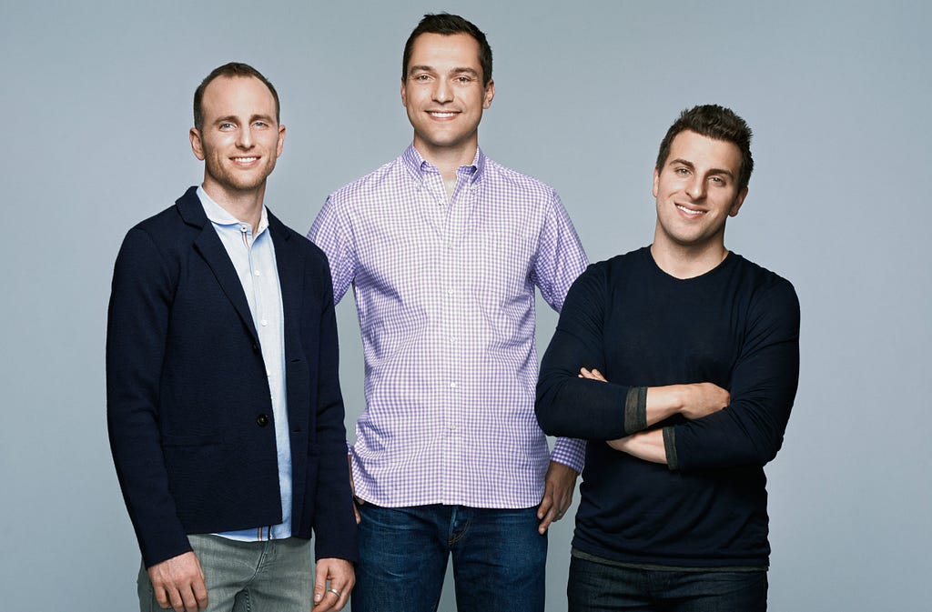 The three founders of Airbnb standing and smiling together