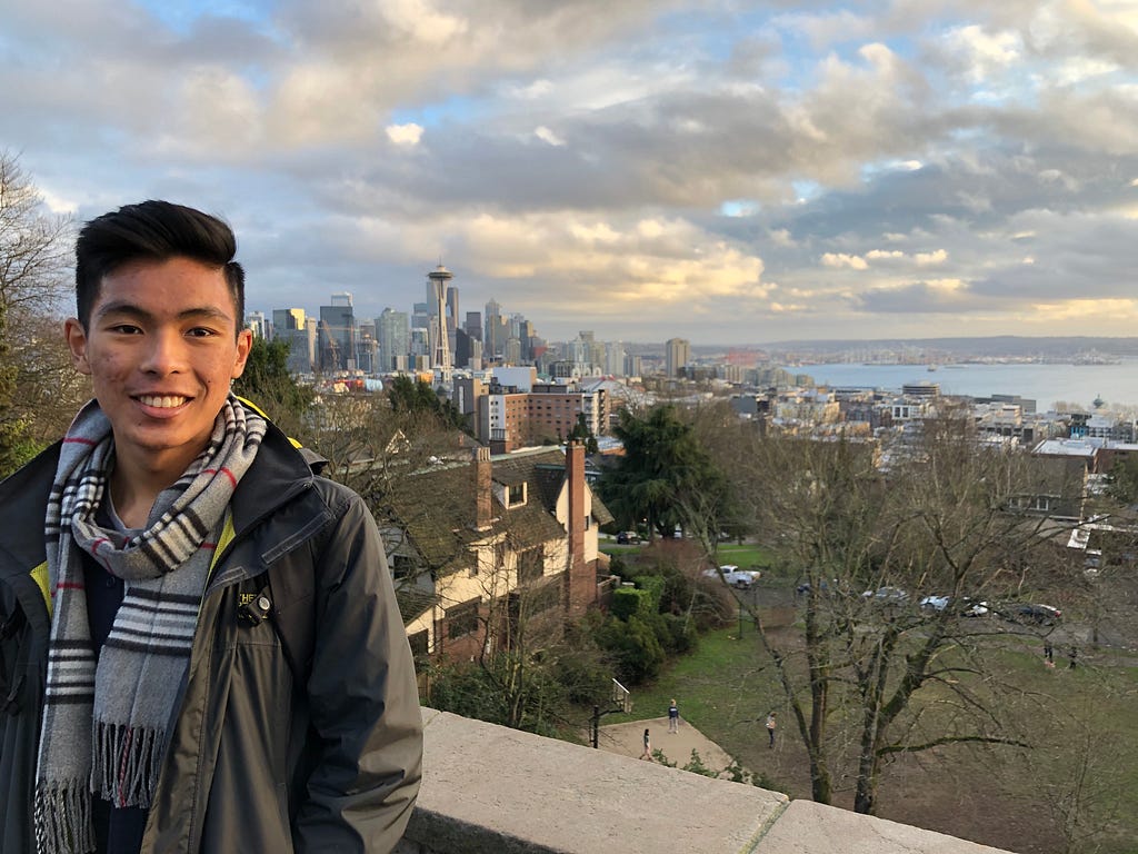 Henry smiles in front of a view that overlooks Seattle.