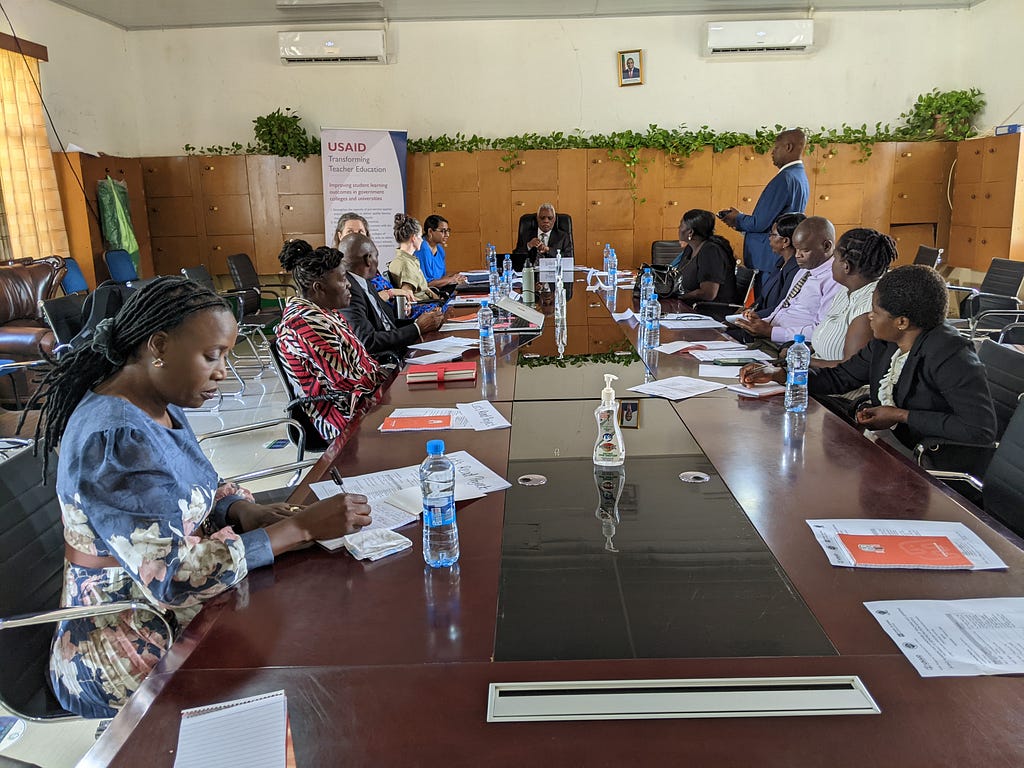 People sit around a large conference table covered with water bottles and papers.