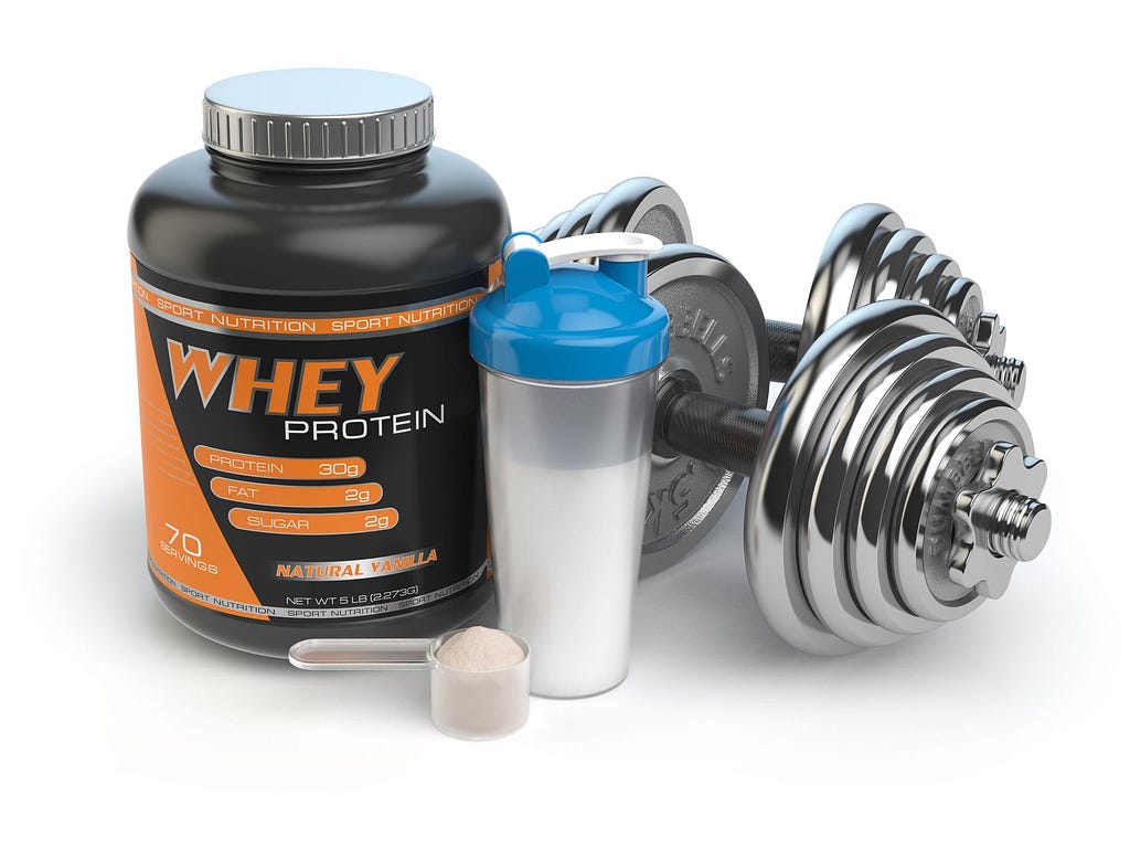 Tub of Protein powder next to a shaker jug and a pair of dumbbells