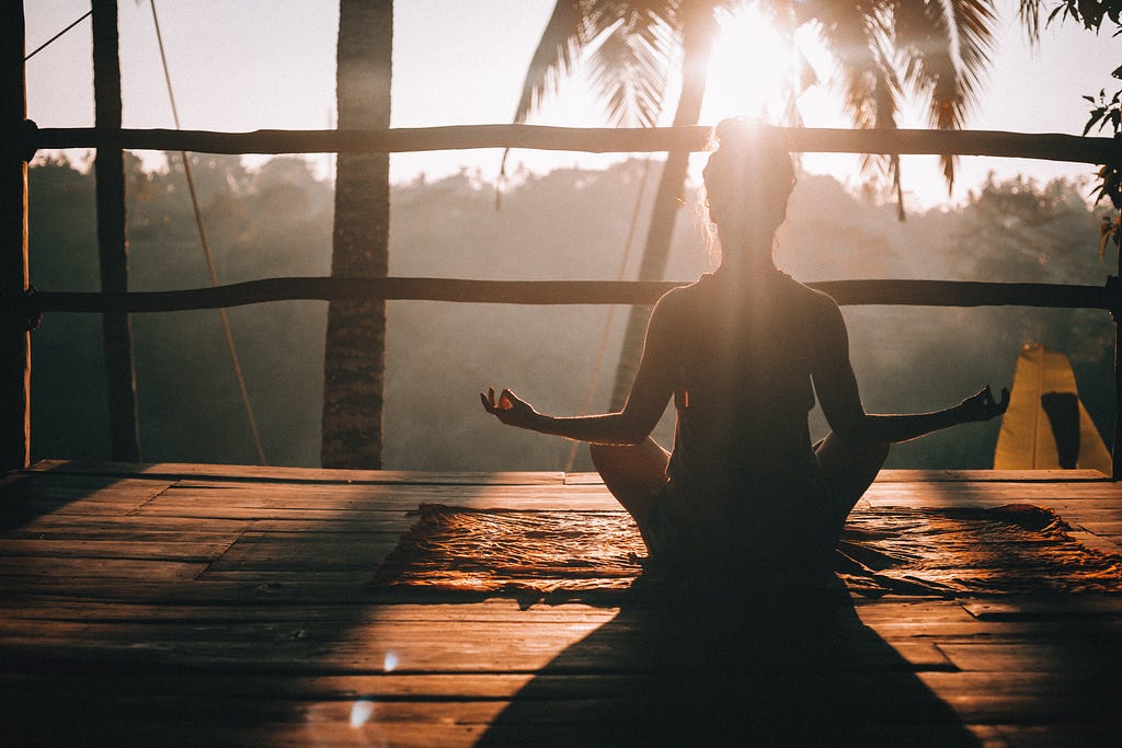 A person meditating on a mat outside. A person meditating on a mat outside.