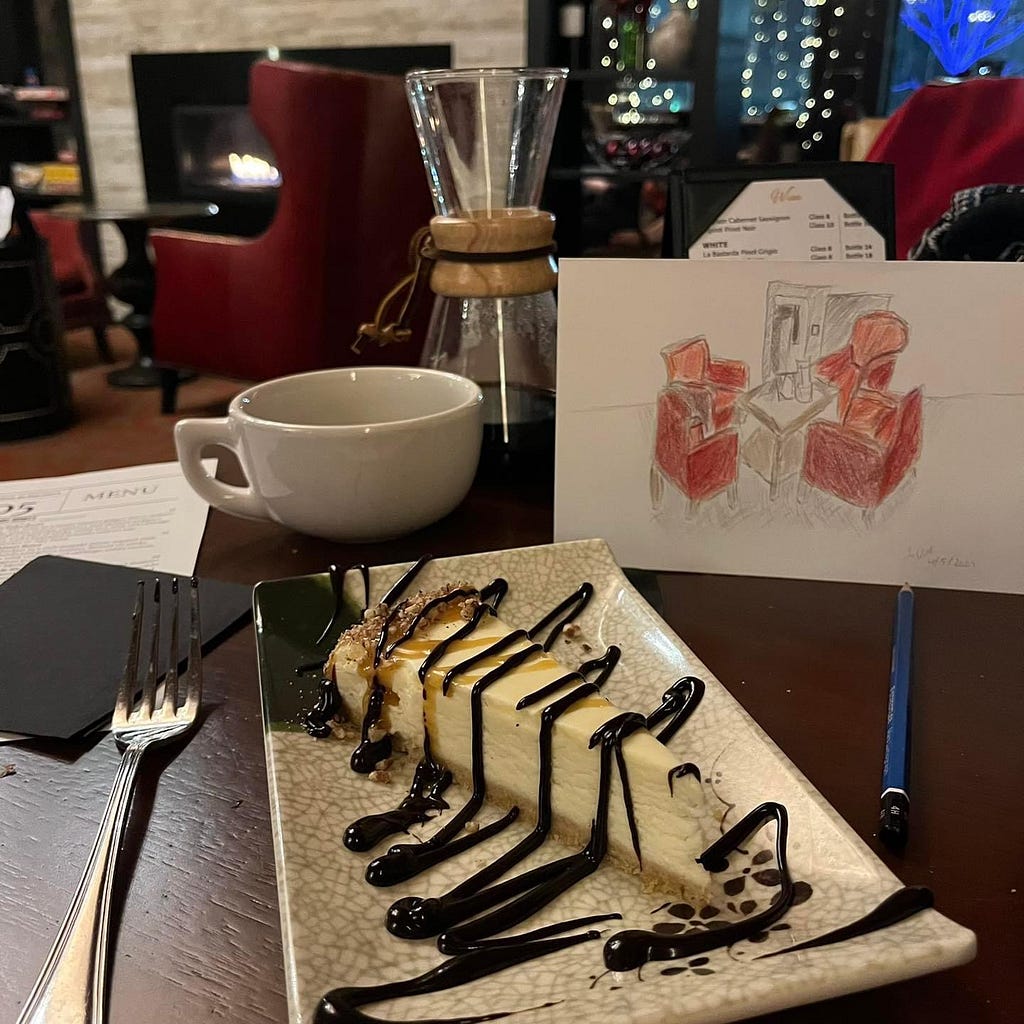 A photo of the turtle cheesecake and pour over coffee at Cee Cee’s with a colored pencil drawing on some of the seating on their lounge side.