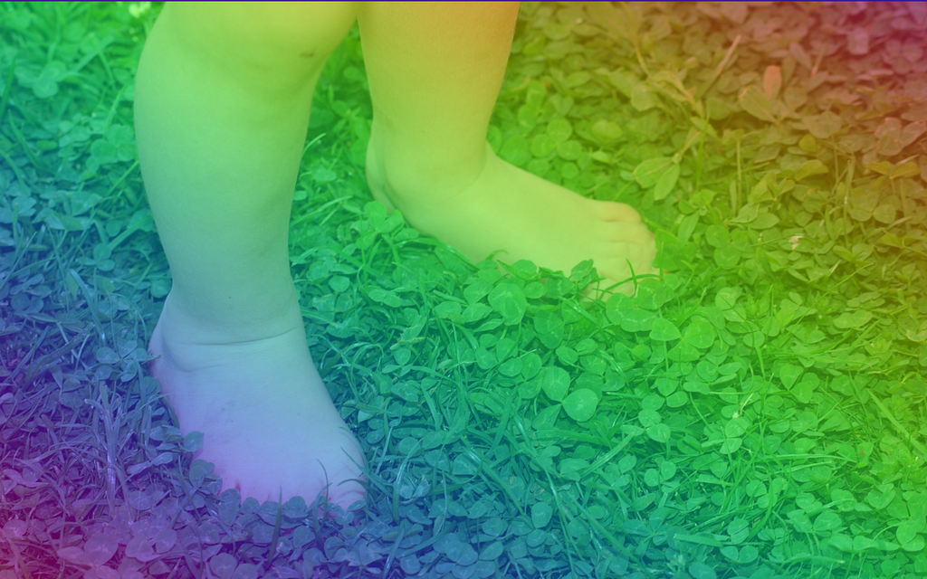 Baby feet in the grass with a rainbow filter