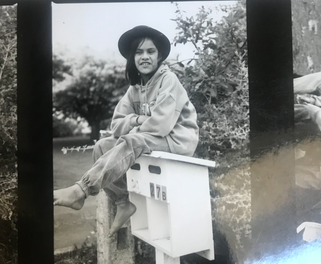 A photo of me sitting on a letterbox as a kid