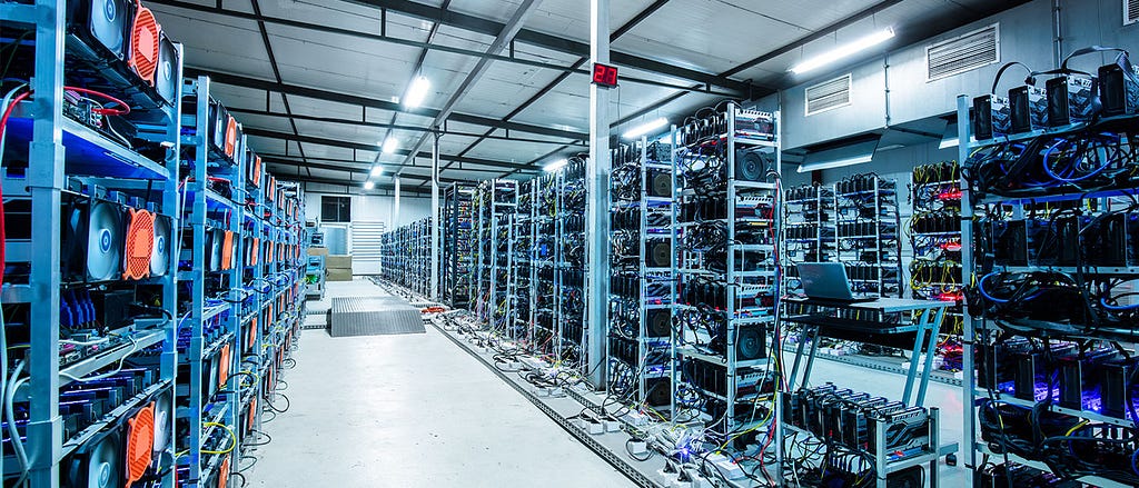 A corridor of a server farm lined with tall racks of computers used for mining cryptocurrency.