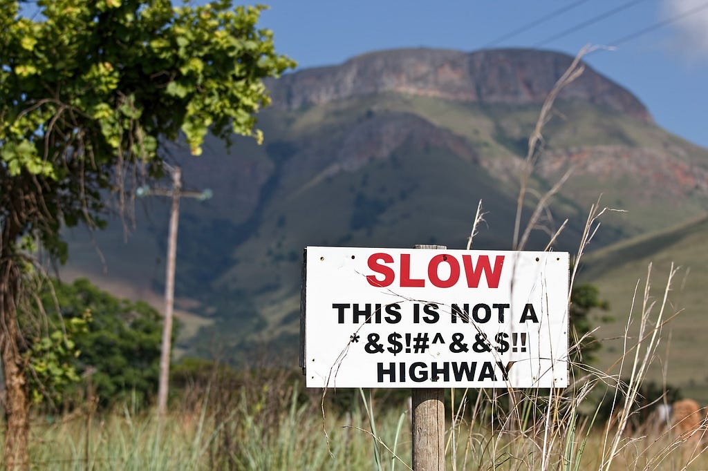 A funny traffic signboard saying, “Slow, This is not a fucking highway”.