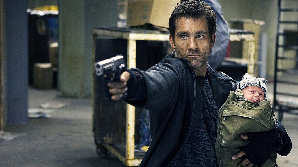 Clive Owen shoots a gun while holding a baby in Shoot ’Em Up (2007)