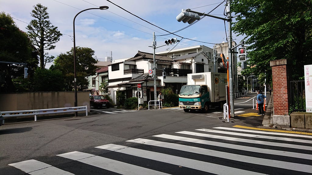 Beyond a zebra crossing on a wide road, the beginnings of an old Tokyo neighbourhood