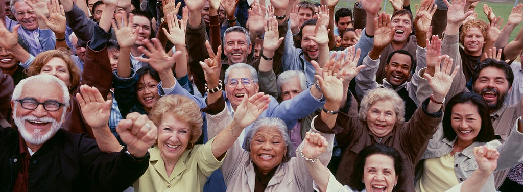Diverse of happy people, many elders, with hands raised in the air.