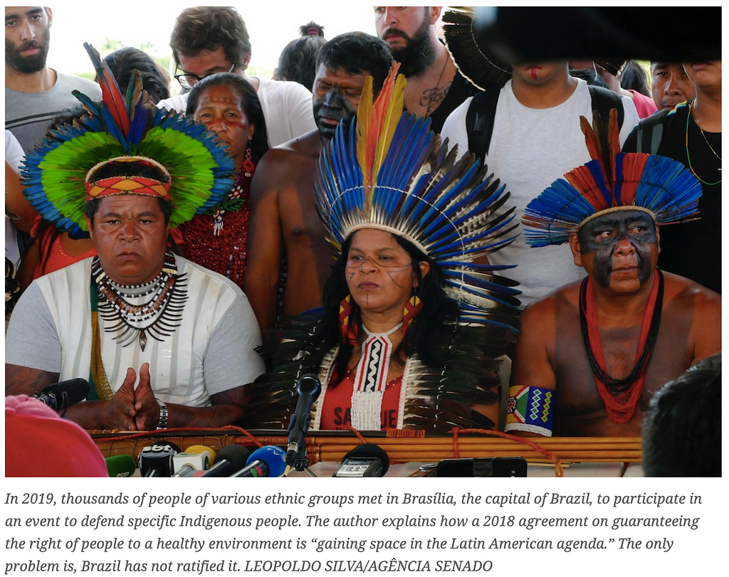 An image 3 people in traditional dress who took part in a 2019 meeting of indigenous people which drew thousands, in Brazil.