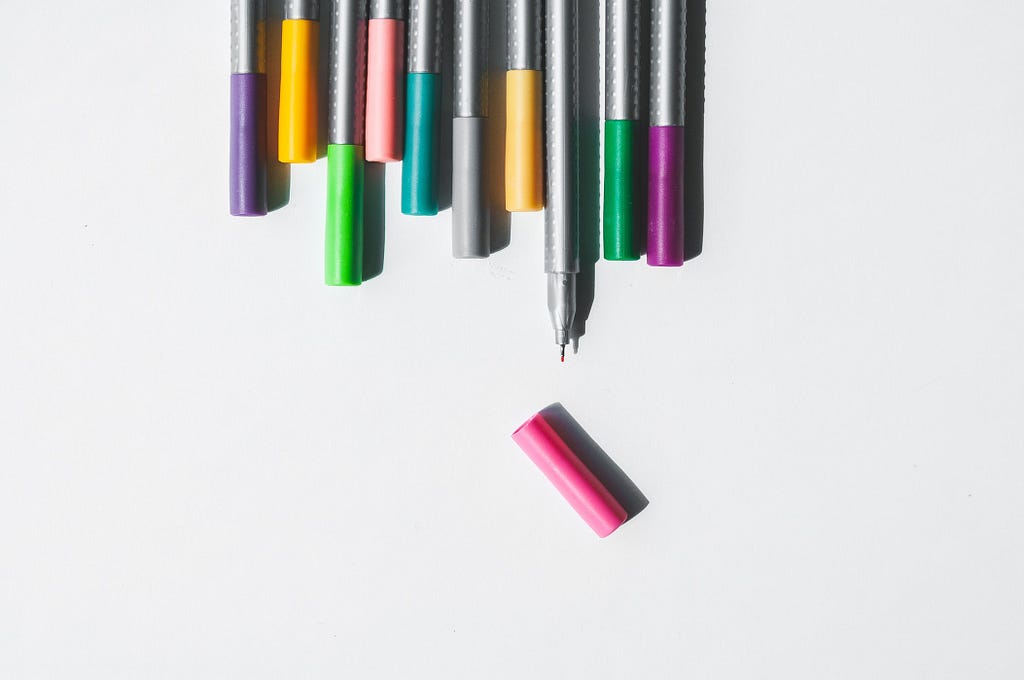 Colorful pens with lids on, except for one.