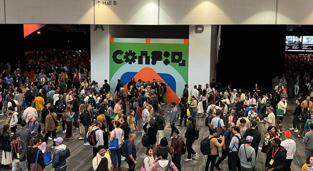 A large crowd of diverse attendees gathered in the main hall of the Config 2024 conference, with the event logo prominently displayed on a large screen at the center of the stage.