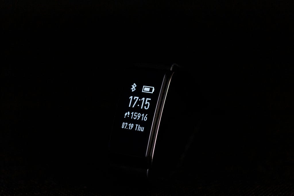 A black background with a digital smart watch showing the time, date, battery, and number of steps.