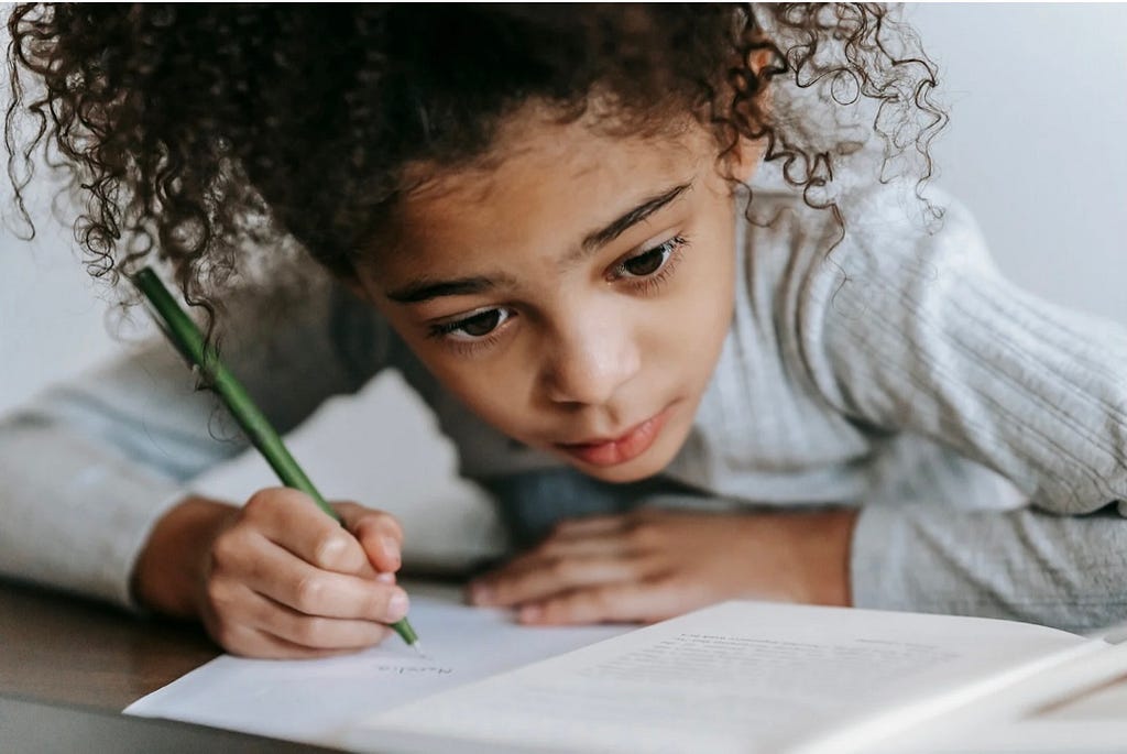 A little girl writing on a book