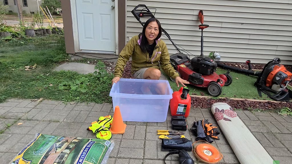 lawnup.net lady kneeling behind plastic bin near lawn mowing equipment