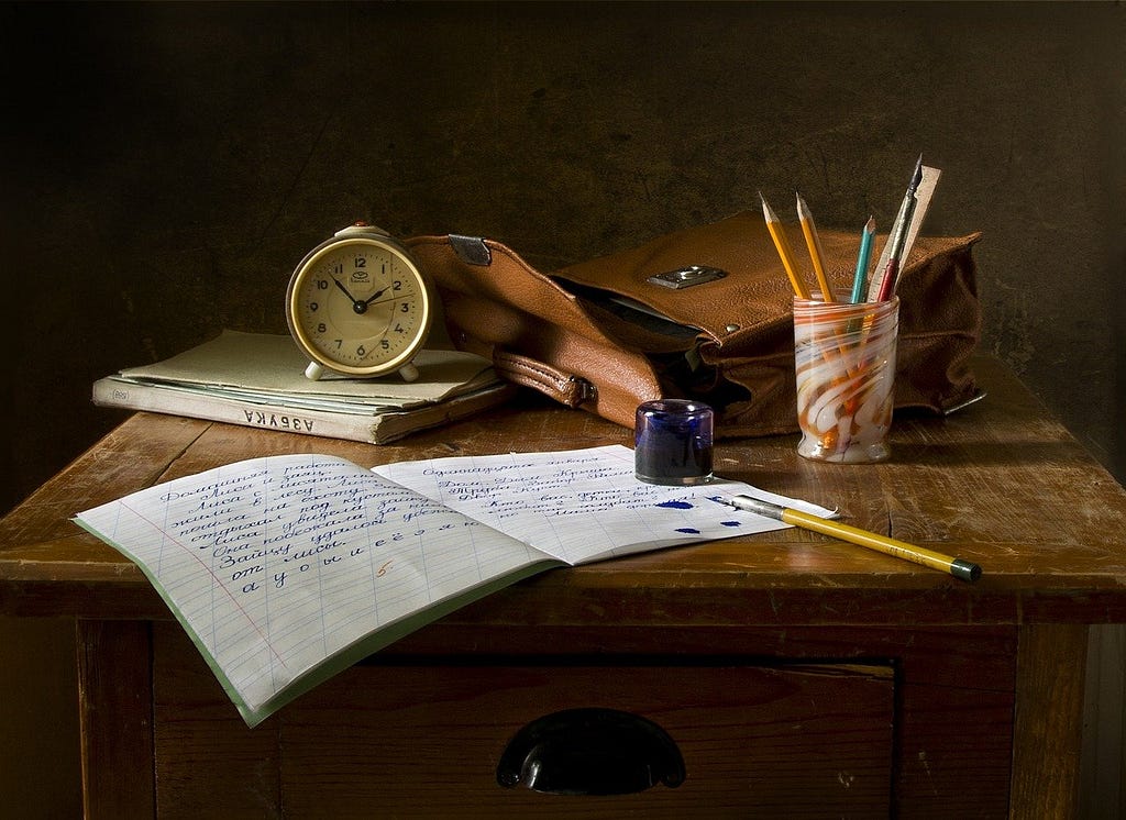 Study desk with a note book, pens and a clock