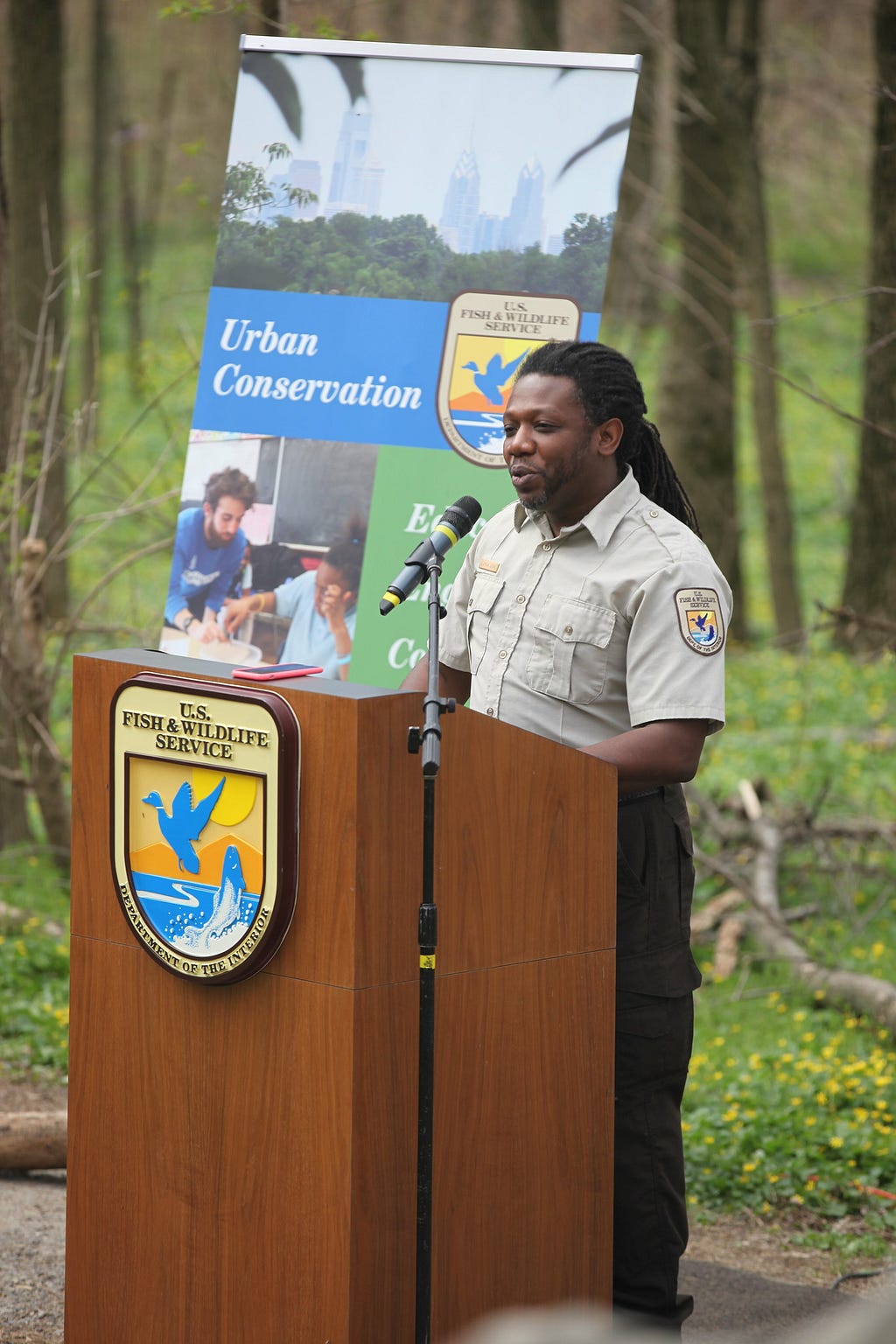 Man in a National Wildlife Refuges uniform speaks at a lectern.