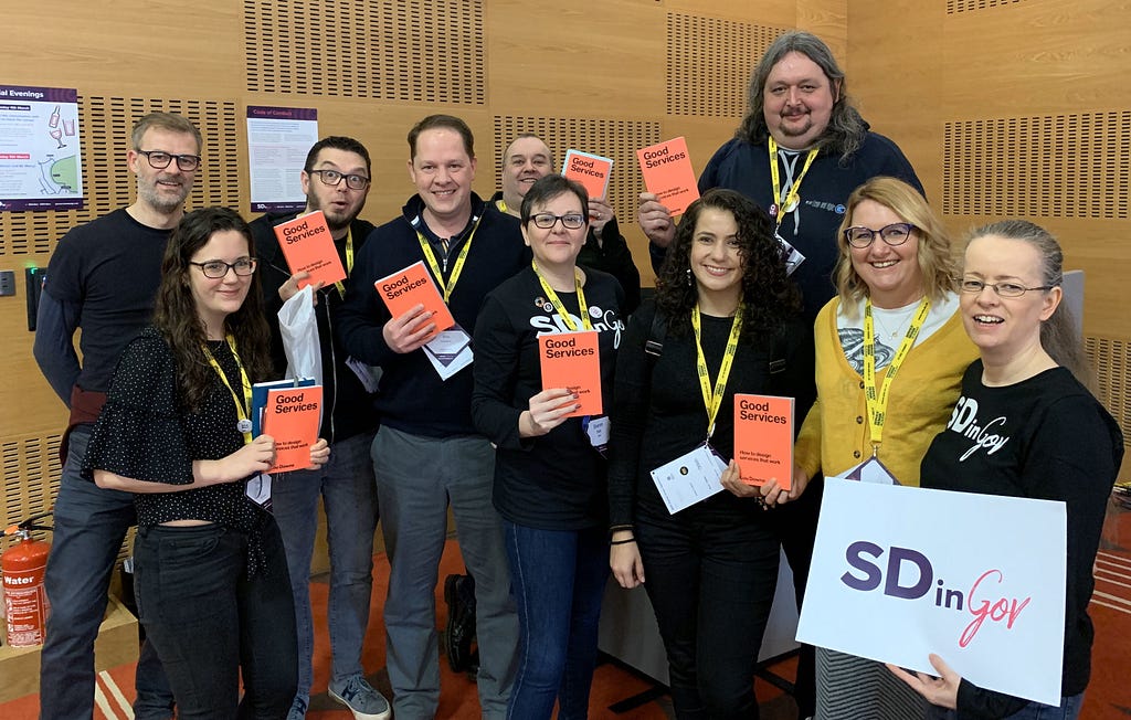 A crowd of people at the Service Design in Government conference show off their new books