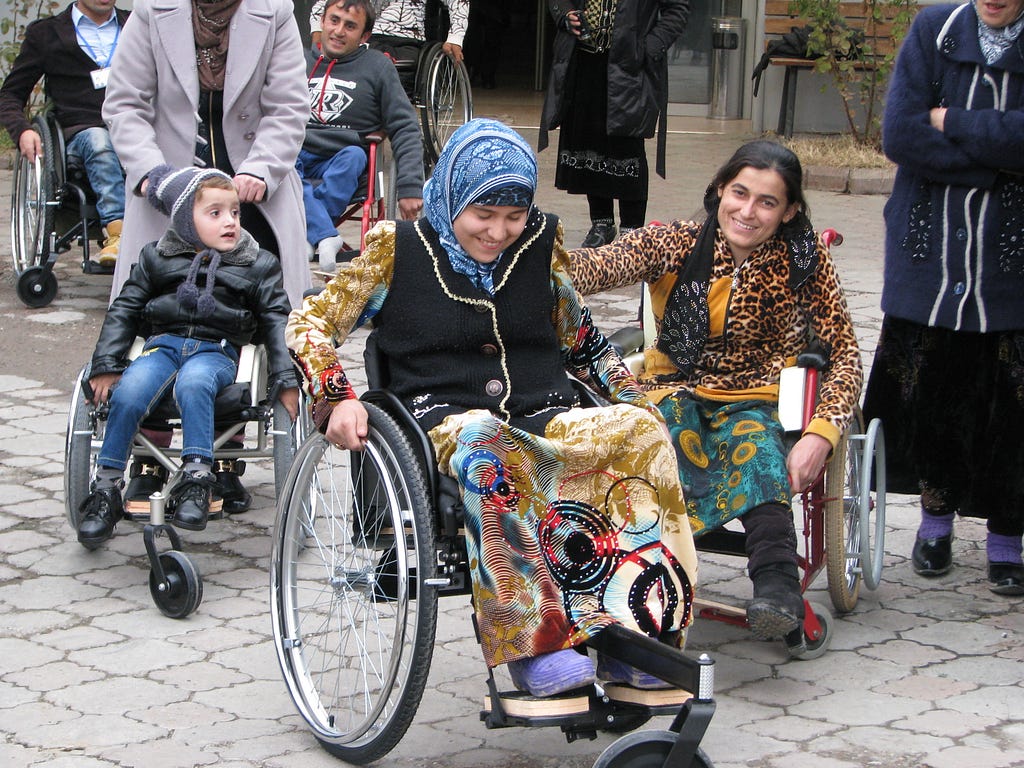 A group of people with and without wheelchairs moving down a street.