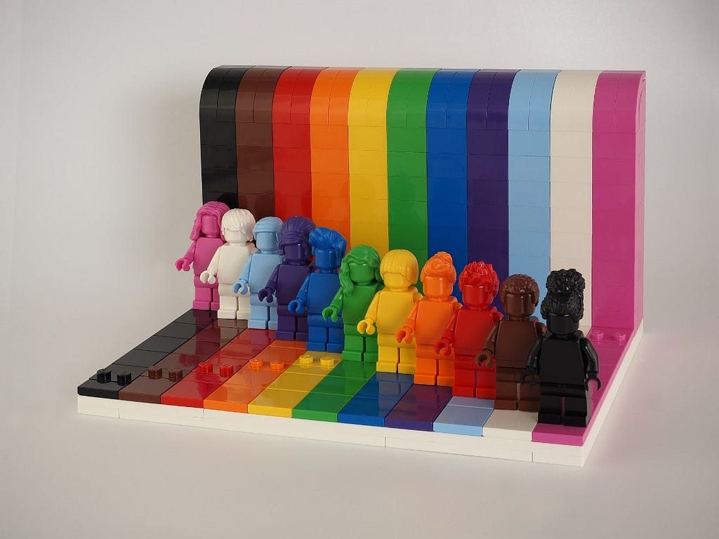 Pink, white, light blue, navy blue, royal blue, green, yellow, orange, red, brown, and black Lego figurines standing side by side.