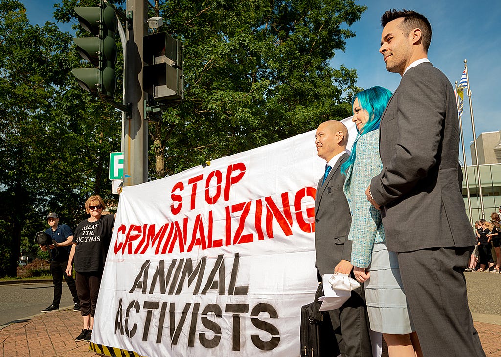 “Excelsior4" animal rights activists Roy Sasano, Nick Schafer, and Amy Soranno stand with supportive animal advocates outside the courthouse in Abbotsford, British Columbia. Canada, 2022. Suzanne Goodwin / We Animals Media