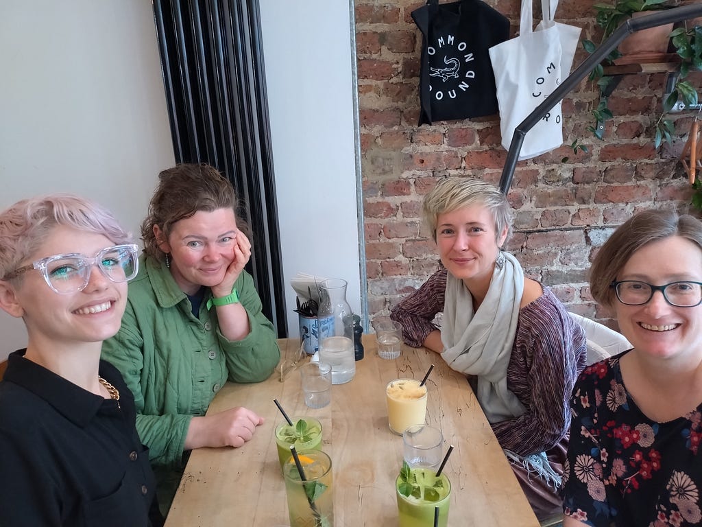 Jasmine, Kate, Ellie and Megan — part of our governance team. Jasmine is a white woman with pink hair and glasses, Kate has a green shirt, Ellie has short hair and a wide scarf and Megan is wearing glasses and a flowery dress and is smiling.