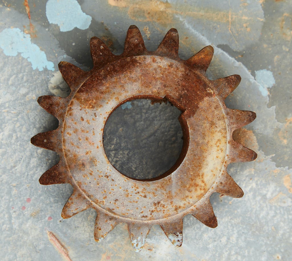 a rusty metal gear wheel that looks like a dirty sun