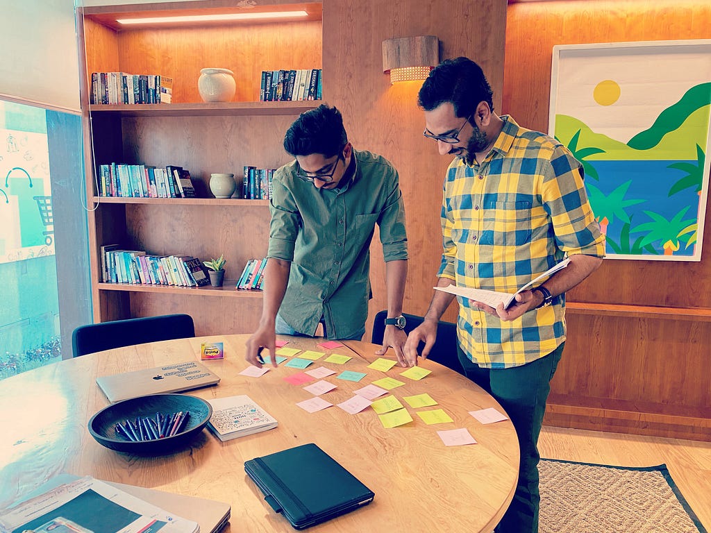 Satyen along with a UX design community member sorting sticky notes at a table.