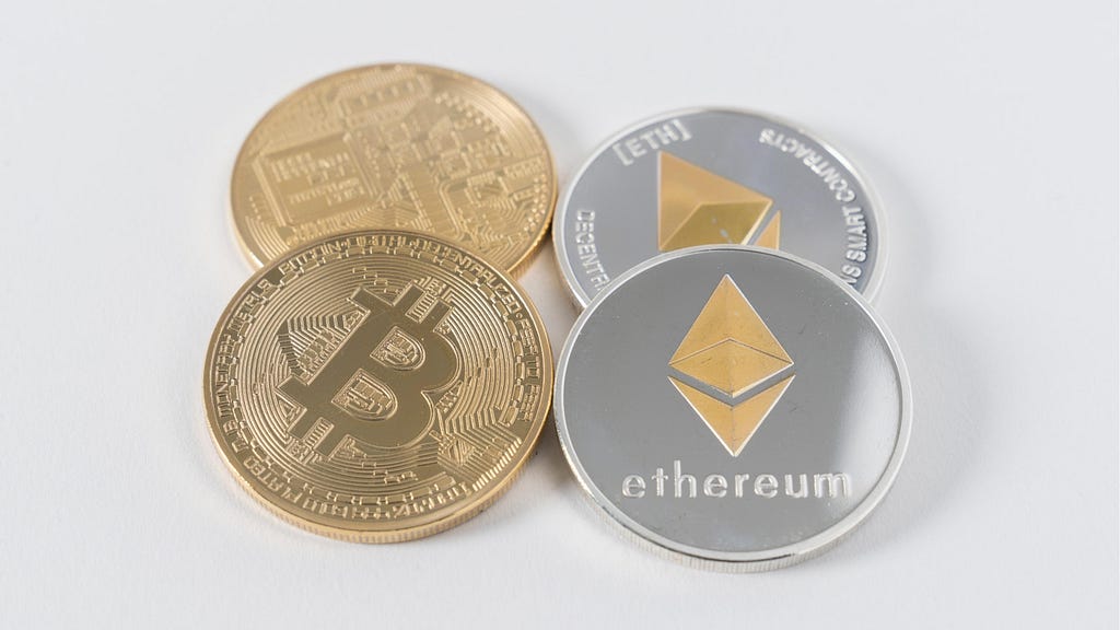 Two physical Bitcoins on the left and two physical Ether coins on the right