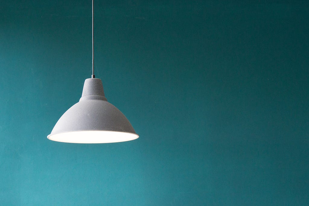 A lighted lamp against a blue wall.