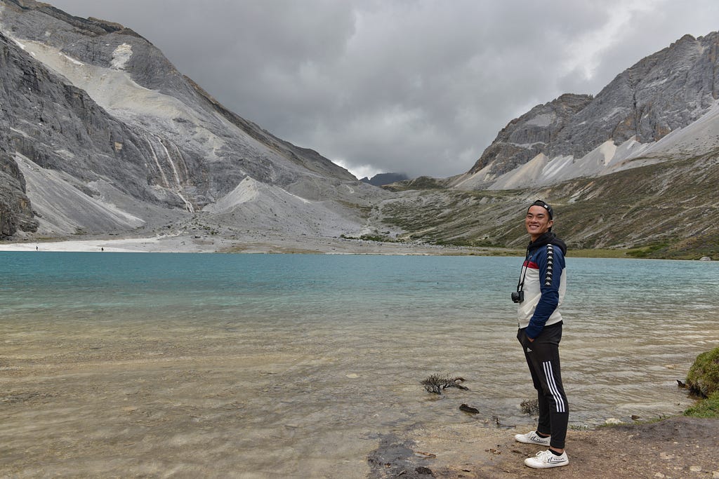 Dennis standing in front of a lake with mountains in the background.