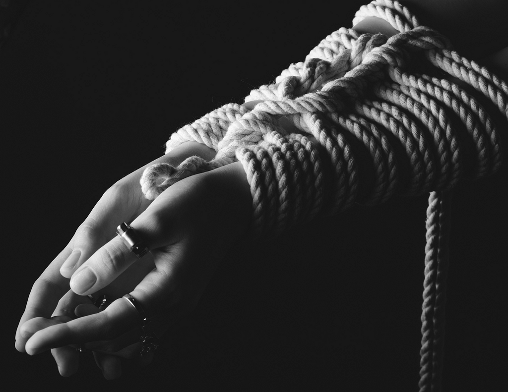 two arms tied together with rope in the style of Shibari, Japanese rope bondage