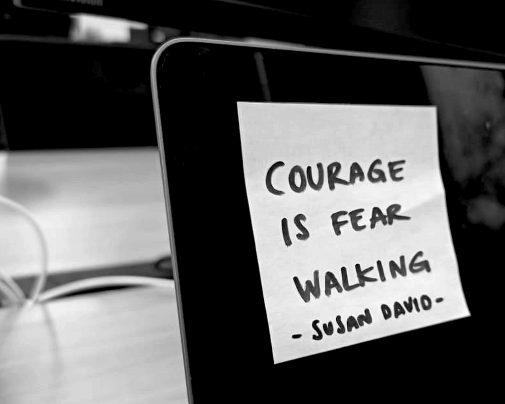 Laptop with a post-it attached saying: ‘Courage is fear walking’ by Susan David