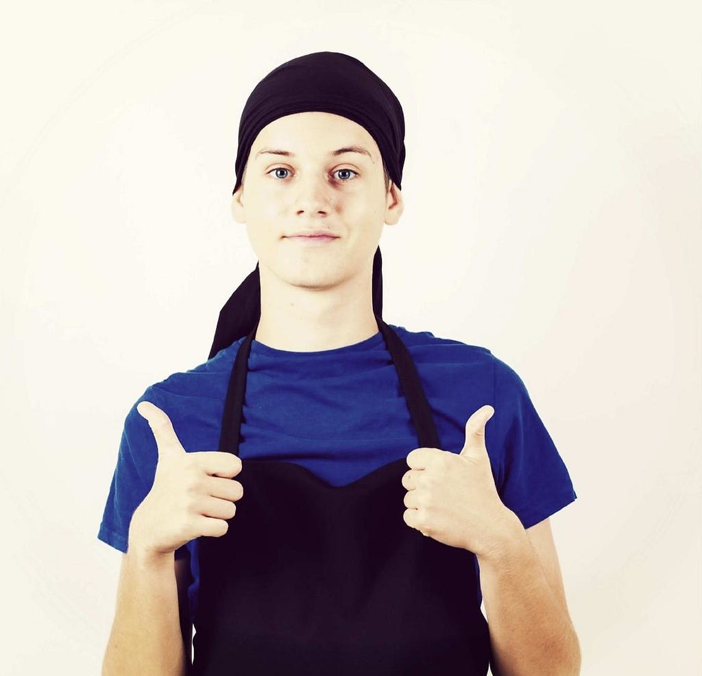 Teen boy in an apron giving two thumbs up