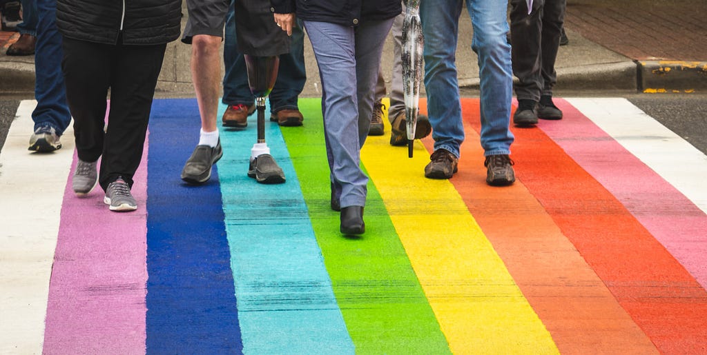 A group of people walking on a road that is painted rainbow colors