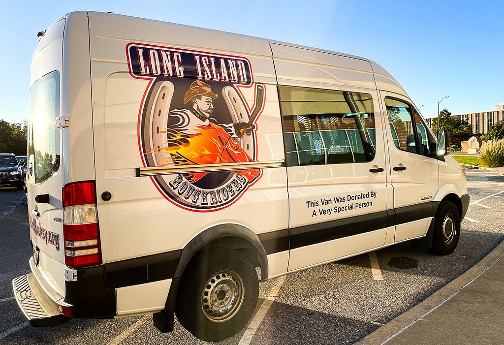 Photo of the LI Sled Hockey Van, which features a logo depicting President Theodore Roosevelt wearing a cowboy hat and a hockey uniform, riding through a lucky horseshoe astride a flaming steed.