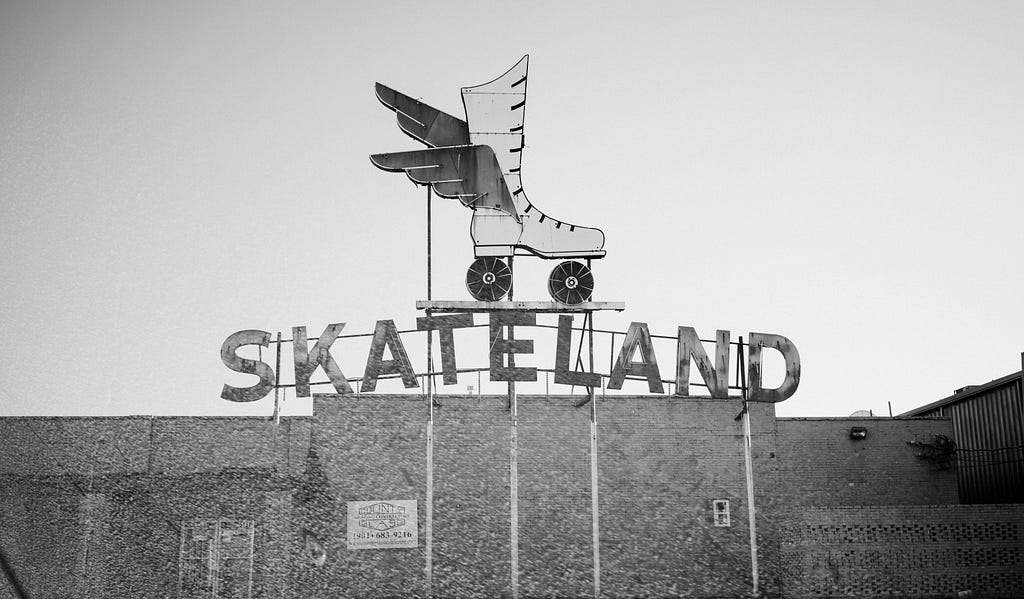 A black and white photo of a vintage sign for Skateland in Memphis, Tennessee including a large roller skate with wings.