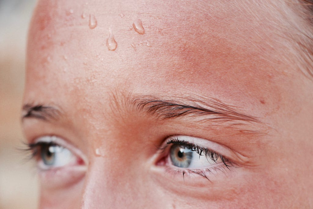 A woman’s forhead with beads of sweat.