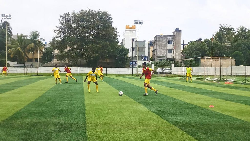 A player wearing a red bib using dribbling, a basic fundamental football skill, to get past an opponent