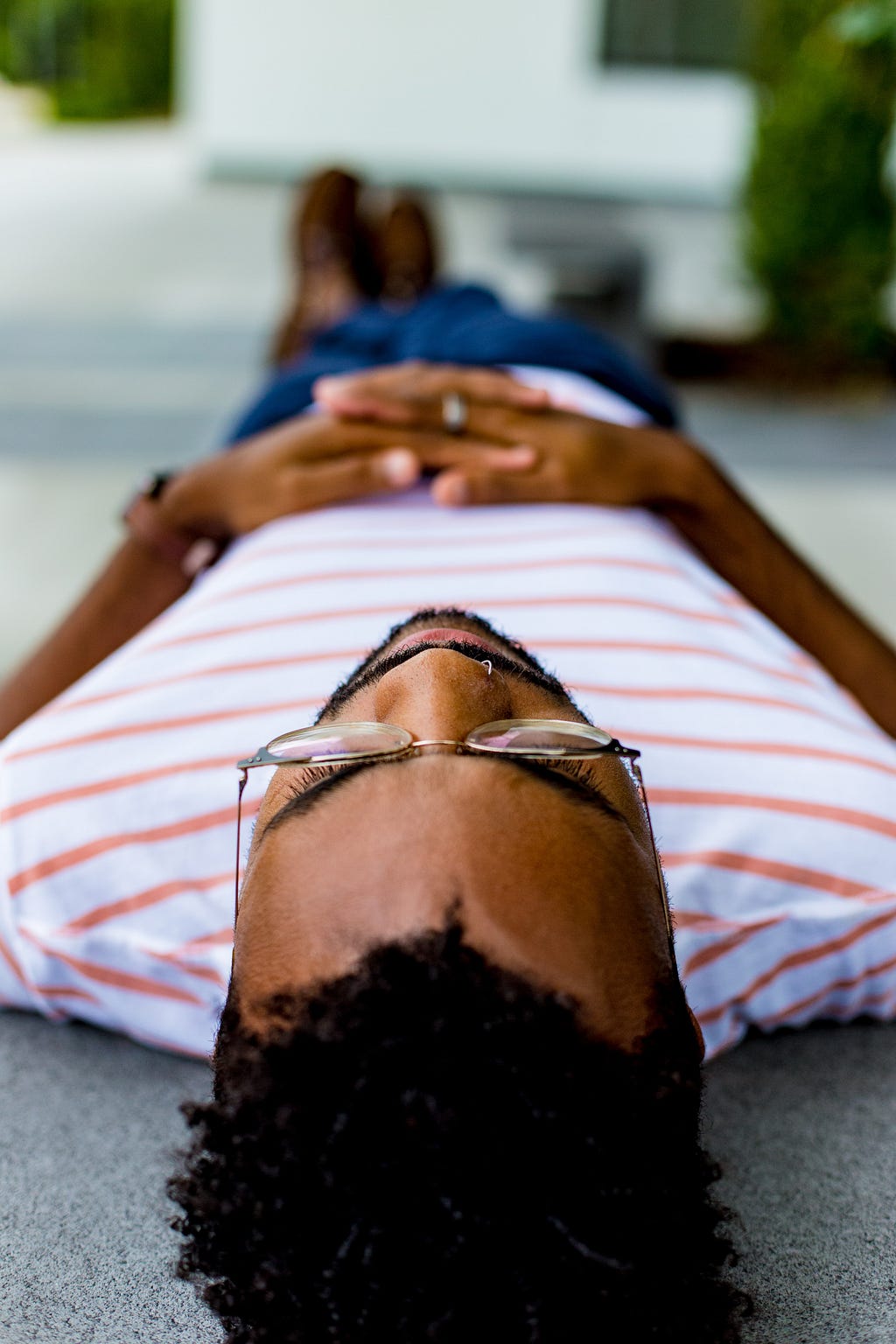A man in a striped shirt lies on the ground while meditating.