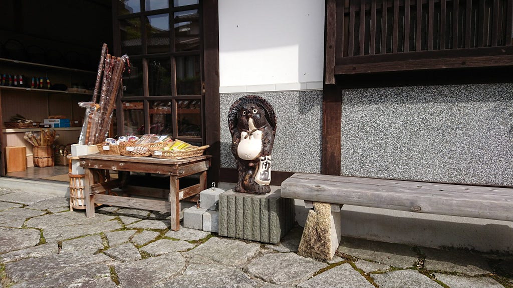 A smiling Tanuki statue outside a shop