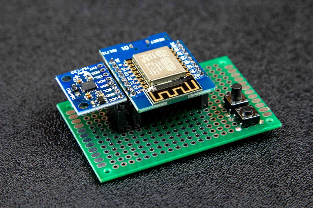 A green perf board is shown with two buttons, a D1 Mini and an MPU6050 accelerometer attached.