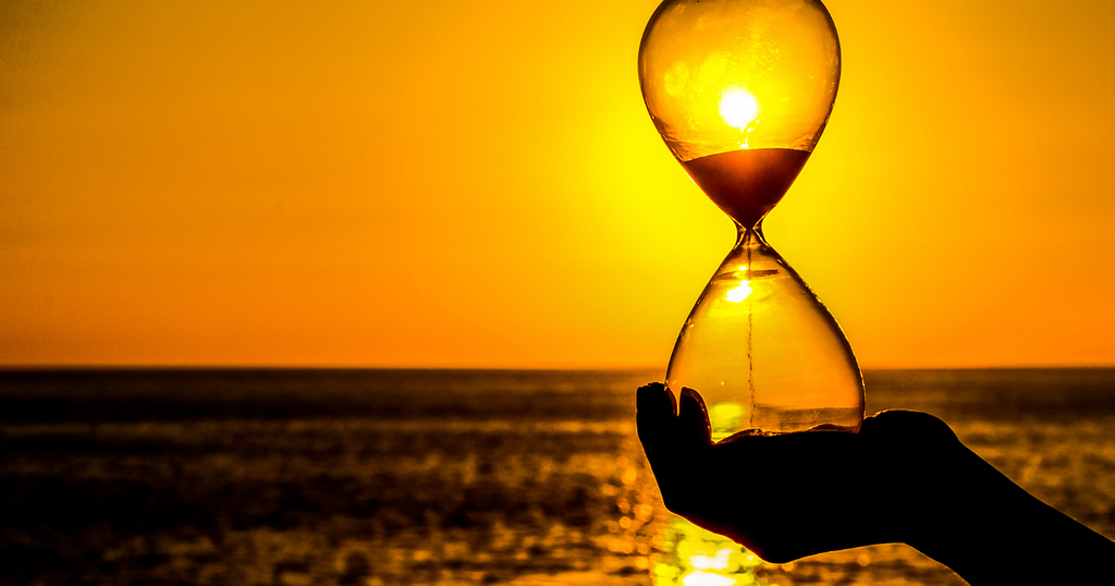 An hourglass by a beach during sunest. A lack of time for hobbies, family, and side-projects is a major cause of physician burnout, according to Gregory Charlop, MD