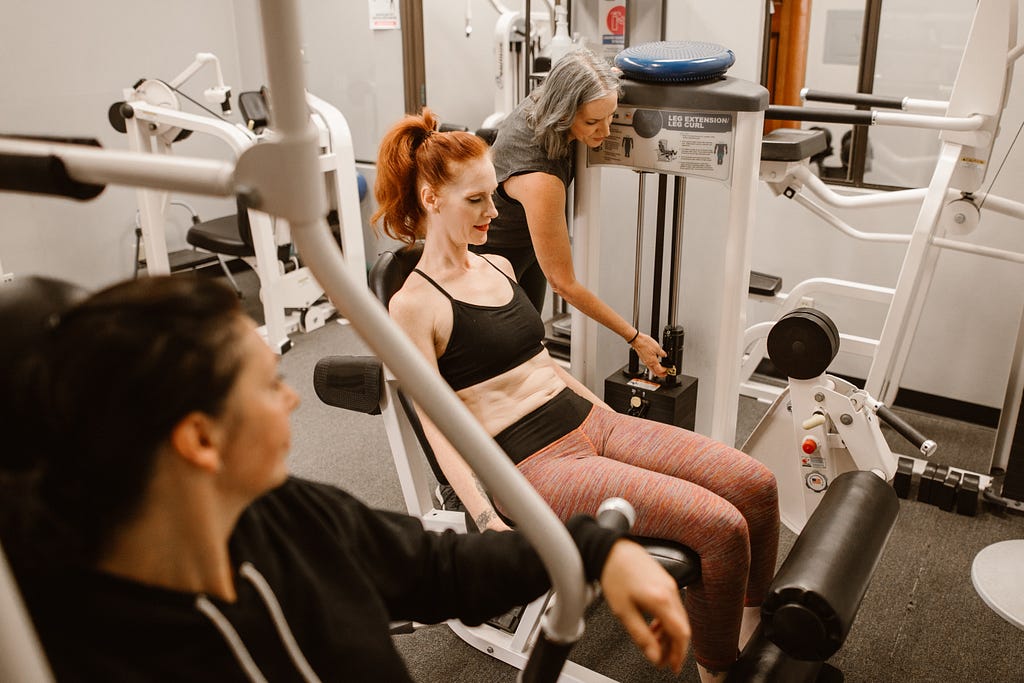 Three women working out in a gym. Prostaglandins and menstrual cramps.
