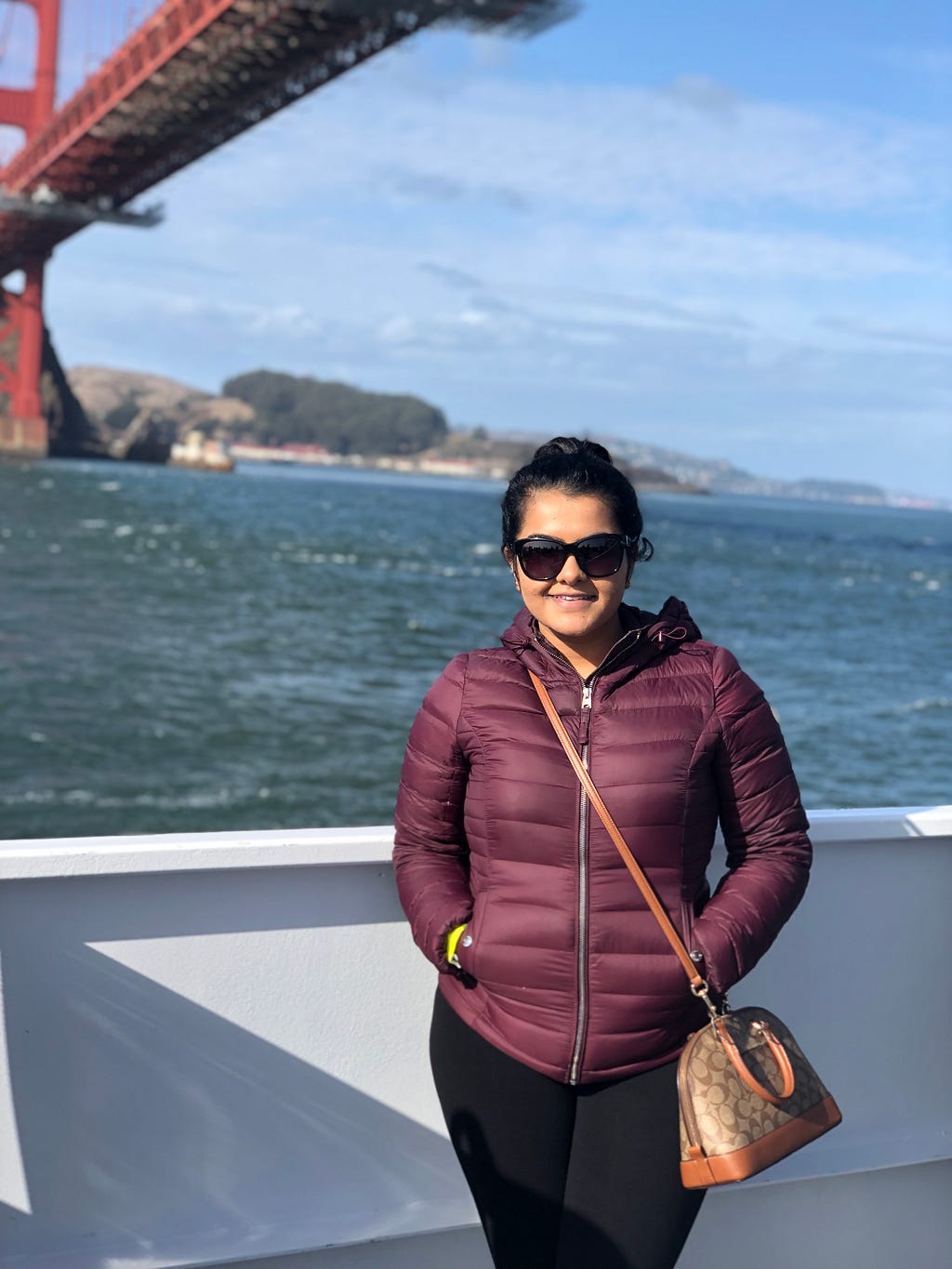 Juhi standing on the deck of a boat under the Golden Gate bridge.